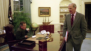 PPresident Bush seated at desk with Baker standing on other side of the desk.