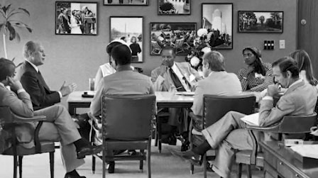 Gerald Ford at conference table with Jim Baker and seven others in a meeting room