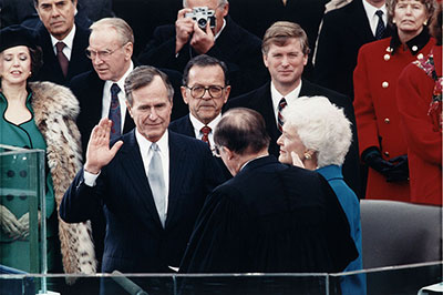 President George H. W. Bush holding up right hand taking oath