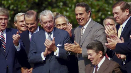Several men clapping as Reagan signs tax law